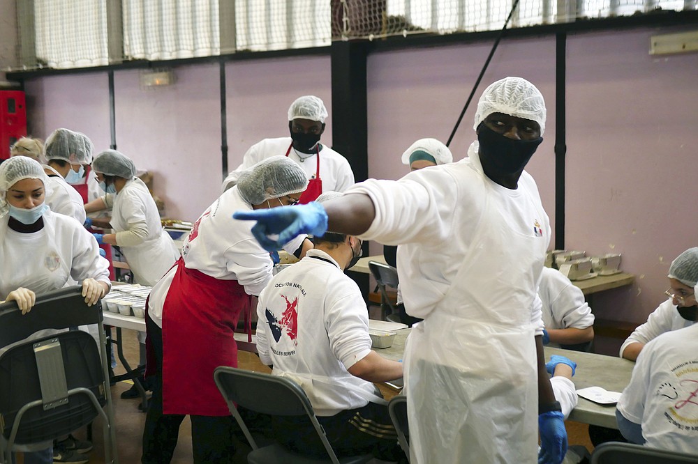 Member of 'Laissez Les Servir' (Let Them Serve) Alioune gestures during meal preparation in Pierrefitte-sur-Seine, north of Paris, Thursday, April 29, 2021. Nourouddine Abdoulhoussen, a former member of the 8th Marine Infantry Parachute Regiment, runs a tight ship, reaching into his years in the military to inculcate in his proteges, youths from poor French suburbs, confidence, courage and love of France. To the youth in (Let Them Serve) the white-bearded 53-year-old leader with the booming voice is “the Captain.” (AP Photo/Thibault Camus)