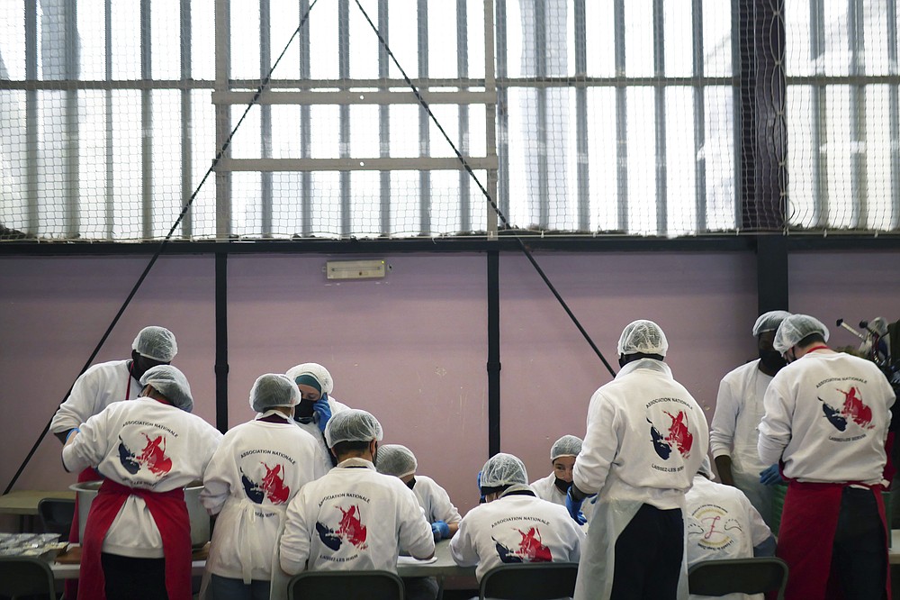 Members of 'Laissez Les Servir' (Let Them Serve) attend a briefing prior to meal preparation in Pierrefitte-sur-Seine, north of Paris, Thursday, April 29, 2021. Nourouddine Abdoulhoussen, a former member of the 8th Marine Infantry Parachute Regiment, runs a tight ship, reaching into his years in the military to inculcate in his proteges, youths from poor French suburbs, confidence, courage and love of France. To the youth in (Let Them Serve) the white-bearded 53-year-old leader with the booming voice is “the Captain.” (AP Photo/Thibault Camus)