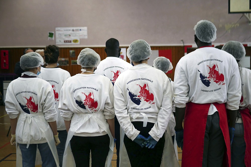 Members of 'Laissez Les Servir' (Let Them Serve) attend a briefing prior to meal preparation in Pierrefitte-sur-Seine, north of Paris, Thursday, April 29, 2021. Nourouddine Abdoulhoussen, a former member of the 8th Marine Infantry Parachute Regiment, runs a tight ship, reaching into his years in the military to inculcate in his proteges, youths from poor French suburbs, confidence, courage and love of France. To the youth in (Let Them Serve) the white-bearded 53-year-old leader with the booming voice is “the Captain.” (AP Photo/Thibault Camus)