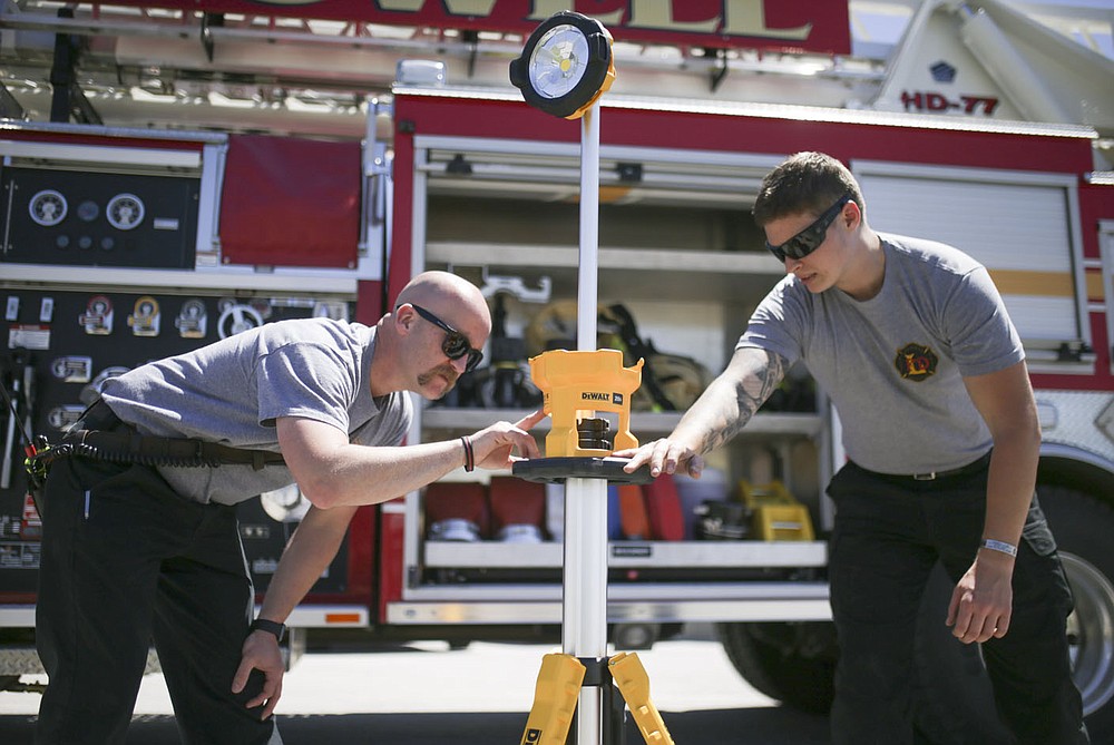 Firefighter and driver Stephen Magner (from left) and firefighter Hayden Johnson inspect a scene light, Friday, April 30, 2021 at the Lowell Fire Department in Lowell. Lowell will hold a special election May 10 for voters to extend a current 1 cent sales tax which funds about 70 percent of the city's operating budget. A bulk of the money goes to the fire department, police department and roads. Check out nwaonline.com/210501Daily/ for today's photo gallery.
(NWA Democrat-Gazette/Charlie Kaijo)