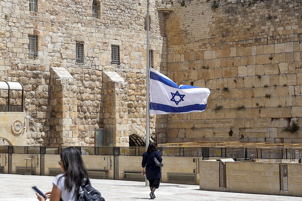Israel's national flag is lowered to half-mast as the country observes a day of mourning after the death of 45 ultra-Orthodox Jews in a stampede at a religious festival at Mt. Meron last Friday, at the plaza in front of the Western Wall, Judaism's holiest prayer site, in Jerusalem's Old City, Sunday, May 2, 2021. Officials came under growing scrutiny Sunday for ignoring warnings about safety lapses at one of Israel’s most visited holy sites, as the country mourned 45 ultra-Orthodox Jews killed in a stampede at a festival there. (AP Photo/Mahmoud Illean)
