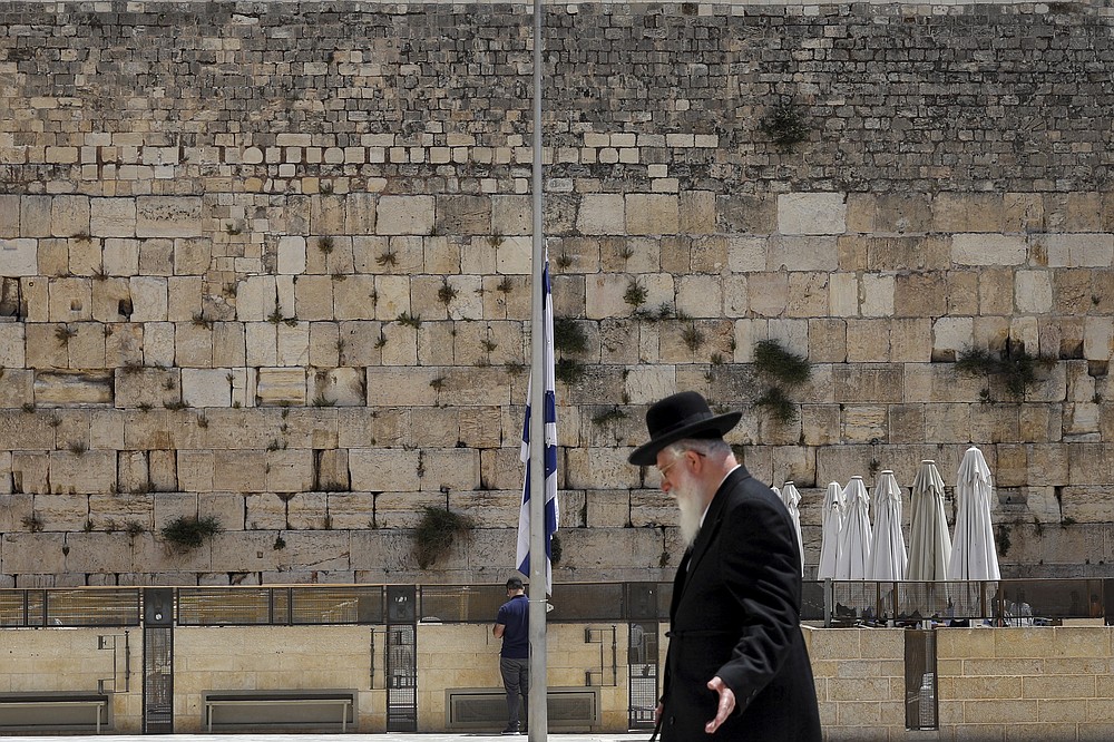 Israel's national flag is lowered to half-mast as the country observes a day of mourning after the death of 45 ultra-Orthodox Jews in a stampede at a religious festival at Mt. Meron last Friday, at the plaza in front of the Western Wall, Judaism's holiest prayer site, in Jerusalem's Old City, Sunday, May 2, 2021. Officials came under growing scrutiny Sunday for ignoring warnings about safety lapses at one of Israel’s most visited holy sites, as the country mourned 45 ultra-Orthodox Jews killed in a stampede at a festival there. (AP Photo/Mahmoud Illean)