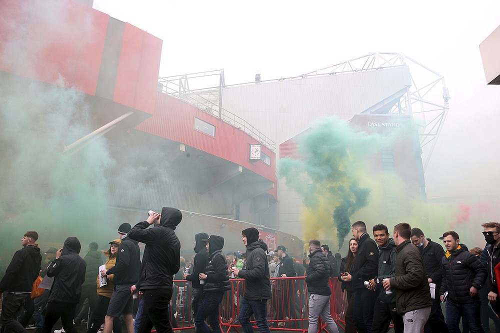 Fans make their way past barriers outside the ground as they let off flares whilst protesting against the Glazer family, owners of Manchester United, before their Premier League match against Liverpool at Old Trafford, Manchester, England, Sunday, May 2, 2021. (Barrington Coombs/PA via AP)