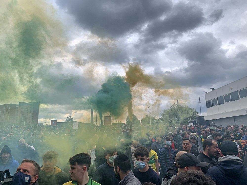 Manchester United fans hold flares as they protest outside of Old Trafford, during a protest against the Glazer family, owners of Manchester United, before their Premier League match against Liverpool at Old Trafford, Manchester, England, Sunday, May 2, 2021. Manchester United supporters have stormed into the stadium and onto the pitch ahead of Sunday's game against Liverpool as fans gathered outside Old Trafford to protest against the ownership. (AP Photo/Rob Harris)