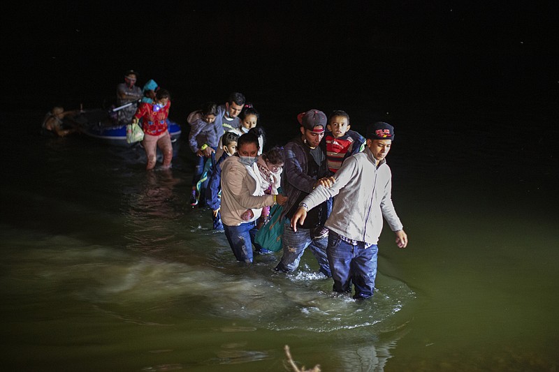 In this March 24, 2021 photo, migrant families, mostly from Central American countries, wade through shallow waters after being delivered by smugglers on small inflatable rafts on U.S. soil in Roma, Texas.  The Biden administration said Monday that four families that were separated at the Mexico border during Donald Trump's presidency will be reunited in the United States this week in what Homeland Security Secretary Alejandro Mayorkas calls “just the beginning” of a broader effort.   (AP Photo/Dario Lopez-Mills)