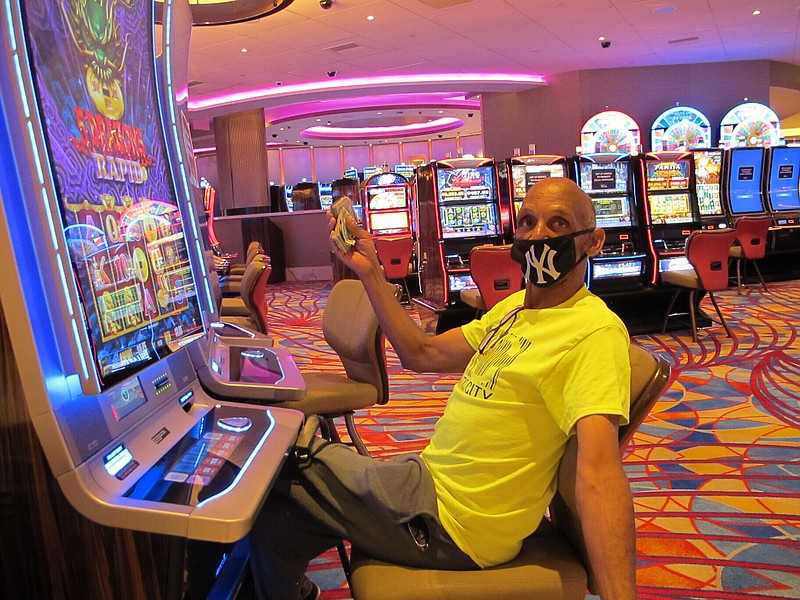 FILE- In this July 2, 2020 file photo, Gary Royster of Atlantic City holds up a wad of cash he used to gamble at the Hard Rock casino in Atlantic City on the day the casino reopened after being shut down for months amid the coronavirus outbreak. On May 3, 2021, Hard Rock officials told The Associated Press they will spend $20 million on renovations, the latest in a line of Atlantic City casinos to reinvest during the coronavirus pandemic. (AP Photo/Wayne Parry, FILE)