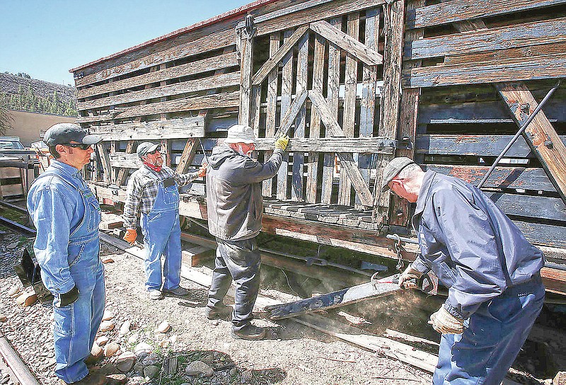 Galloping Goose Historical Society members Chris Pranskatis, Ben Deason, Joe Becker and Bill Wolf, from left, work April 16, 2021, to remove a door from a stock car that was built in 1903 to transport livestock, as they ready the vehicle for display in Dolores, Colo. The historical society is in the process of stabilizing the car and four other types of narrow-gauge railcars to put on display in Dolores. (Jerry McBridge/The Durango Herald via AP)