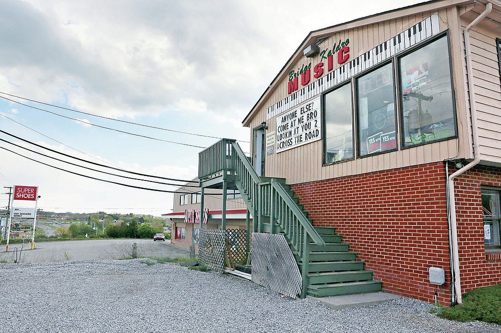 The sign war started with Bridge Kaldro Music and their neighbor Super Shoes, left, in Christiansburg, Va., Thursday, April 22, 2021. It was Bridge Kaldro Music that that touched off this battle royale, challenging businesses to poke silly fun at one another. It has quickly spread across town and gone viral online. (Matt Gentry/The Roanoke Times via AP)