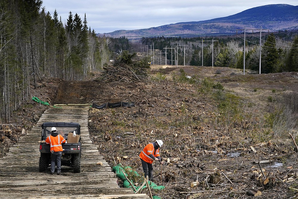 Workers for Northern Clearing pound stakes to mark land on an existing Central Maine Power power line corridor that has been recently widened to make way for new utility poles, Monday, April 26, 2021, near Bingham, Maine. As President Joe Biden's administration plans to fight climate change by weaning the nation off fossil fuels, these large-scale renewable energy projects are the source of conflict within a seemingly unlikely group: environmentalists. (AP Photo/Robert F. Bukaty)