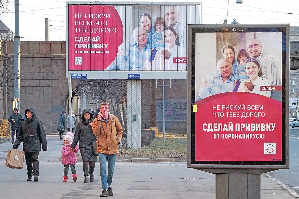 People walk past posters reading "Do not risk everything that is dear to you. Get vaccinated against coronavirus" in St. Petersburg, Russia, Saturday, April 3, 2021. Russia has boasted about being the first country in the world to authorize a coronavirus vaccine and rushed to roll it out earlier than other countries, even as large-scale testing necessary to ensure its safety and effectiveness was still ongoing. (AP Photo/Dmitri Lovetsky)