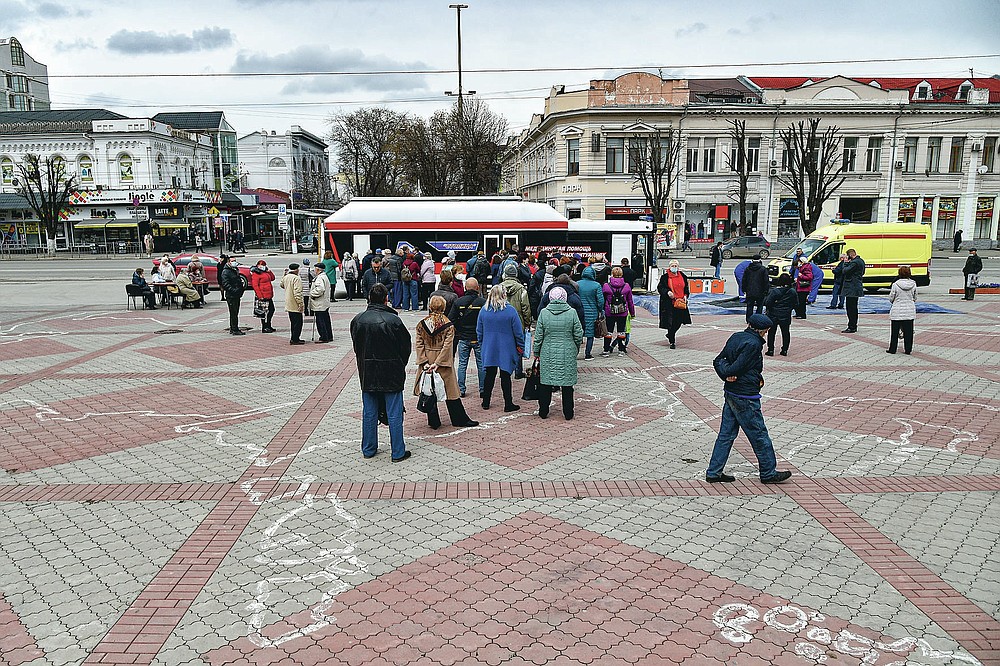 People wearing face masks to protect against coronavirus queue to get a shot of Russia's Sputnik V coronavirus vaccine in a mobile vaccination center in Simferopol, Crimea, Tuesday, April 13, 2021. Russia has boasted about being the first country in the world to authorize a coronavirus vaccine and rushed to roll it out earlier than other countries, even as large-scale testing necessary to ensure its safety and effectiveness was still ongoing. (AP Photo/Alexander Polegenko)