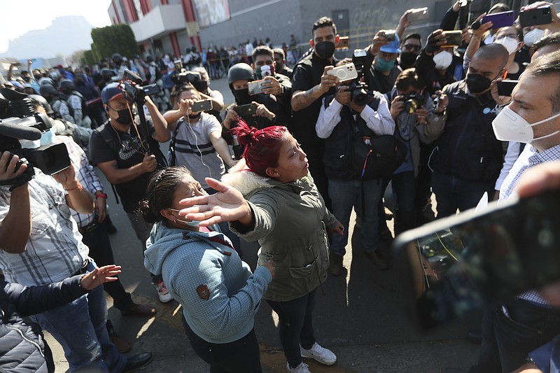 A woman demands information from a lawmaker of people injured when a metro overpass collapsed, near the site of the wreckage in Mexico City, Tuesday, May 4, 2021. The elevated section of the metro's Line 12 collapsed late Monday killing at least 23 people and injuring at least 79, city officials said. (AP Photo/Fernando Llano)