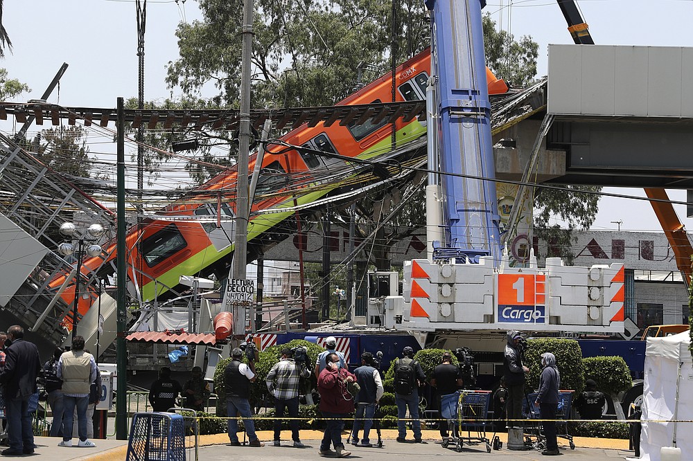 Subways cars are lowered to ground from a collapsed elevated section of the metro, in Mexico City, Tuesday, May 4, 2021. An elevated section of the Mexico City metro collapsed late Monday, killing at least 23 people and injuring at least 79, city officials said. (AP Photo/Marco Ugarte)