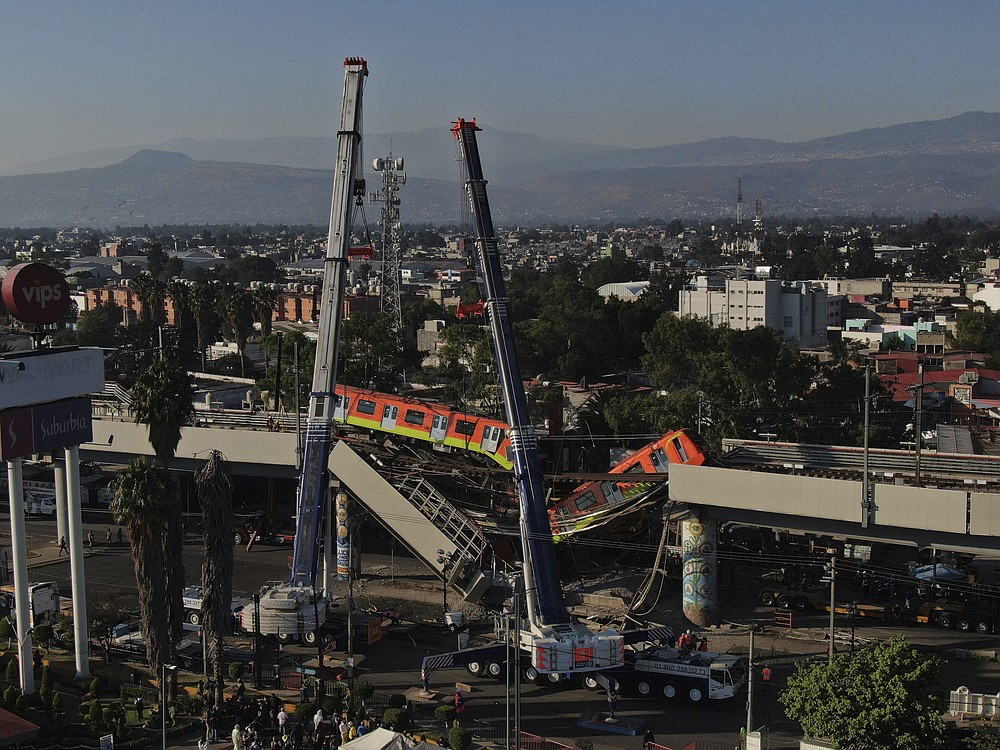 Subway cars dangle at an angle from a collapsed elevated section of the metro, in Mexico City, Tuesday, May 4, 2021. The elevated section of the metro's Line 12 collapsed late Monday killing at least 23 people and injuring at least 79, city officials said. (AP Photo/Fernando Llano)