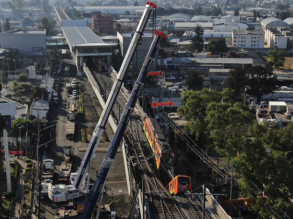 Subway cars dangle at an angle from a collapsed elevated section of the metro, in Mexico City, Tuesday, May 4, 2021. The elevated section of the metro's Line 12 collapsed late Monday killing at least 23 people and injuring at least 79, city officials said. (AP Photo/Fernando Llano)