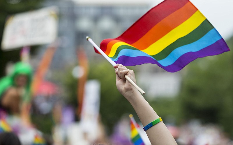A spectator waves a rainbow flag on June 15, 2019, during the annual Northwest Arkansas Pride Festival parade on Dickson Street in Fayetteville. The City Council took up a resolution to affirm the city's welcoming of all people, including transgender residents and visitors. (File photo/NWA Democrat-Gazette/Ben Goff)