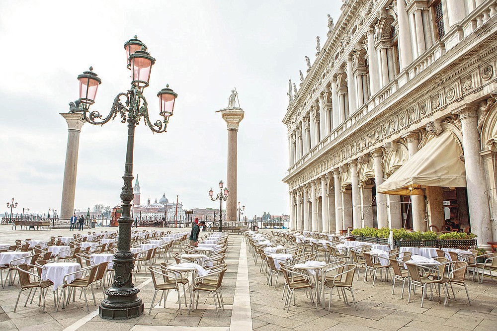 A waiter works in a restaurant in Venice, north Italy, Saturday, May 1, 2021. Italy is slowly reopening after half a year of rotating virus closures allowing outside eating. (Filippo Ciappi/LaPresse via AP)