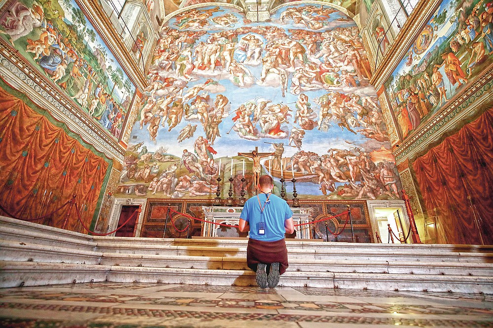 a customer kneels in front of the final Judgement fresco because of the Italian Renaissance painter Michelangelo inside the Sistine Chapel of Vatican Museums in the celebration of this museum's reopening, in Rome, Monday, May 3, 2021. The Vatican Museums reopened Monday to visitors after a shutdown after COVID-19 containment actions. (AP Photo/Alessandra Tarantino)