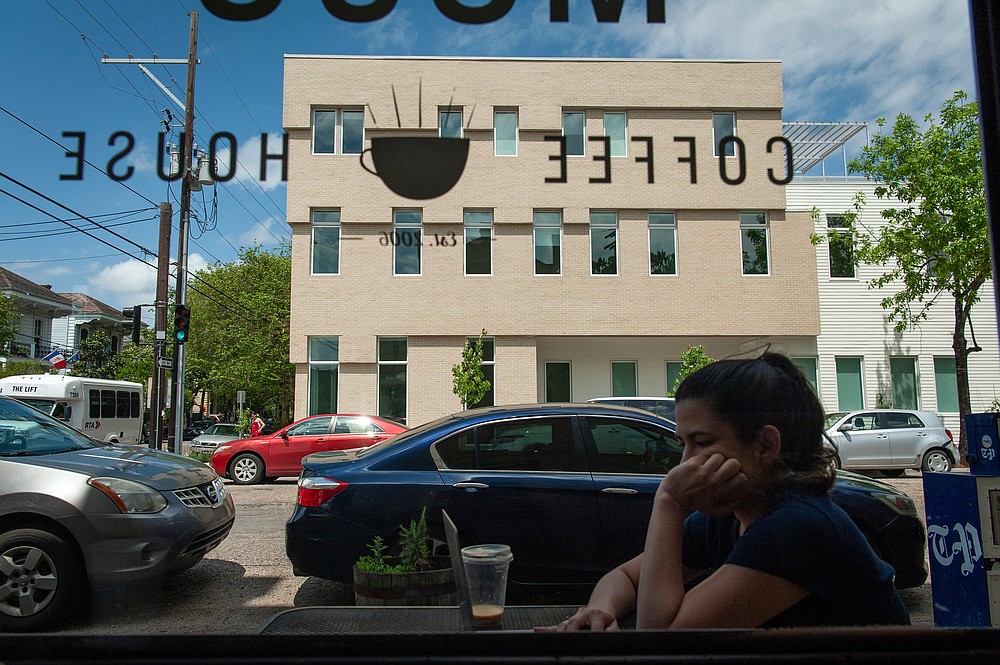 A customer sits at an outdoor table at a coffee shop across the street from the Travelers New Orleans. (Rory Doyle/The New York Times)