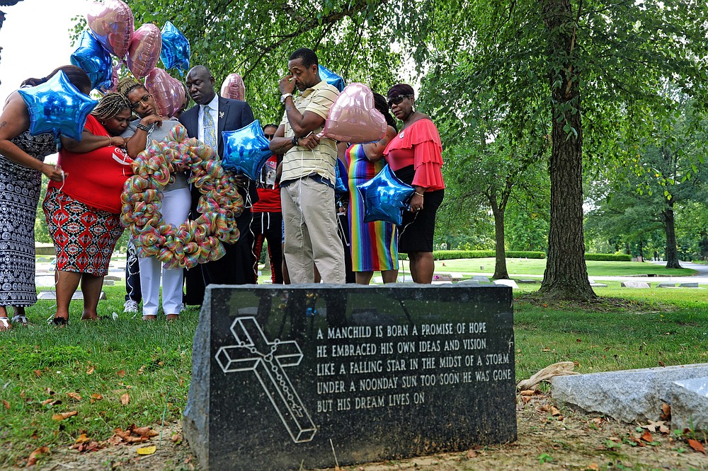FILE - This Friday August 9, 2019, Lesley McSpadden, mother of Michael Brown, is praying with a group of Rainbow of Mothers before laying a large wreath on her son's grave on the fifth anniversary of that death in St. Peter's Cemetery in St. Louis.  Left is Samaria Rice, the mother of Tamir Rice, who was killed by police in Ohio in 2014.  In the center is Ben Crump, her lawyer, and on the right her husband Louis Head.  (Laurie Skrivan / St. Louis Post-Dispatch via AP)