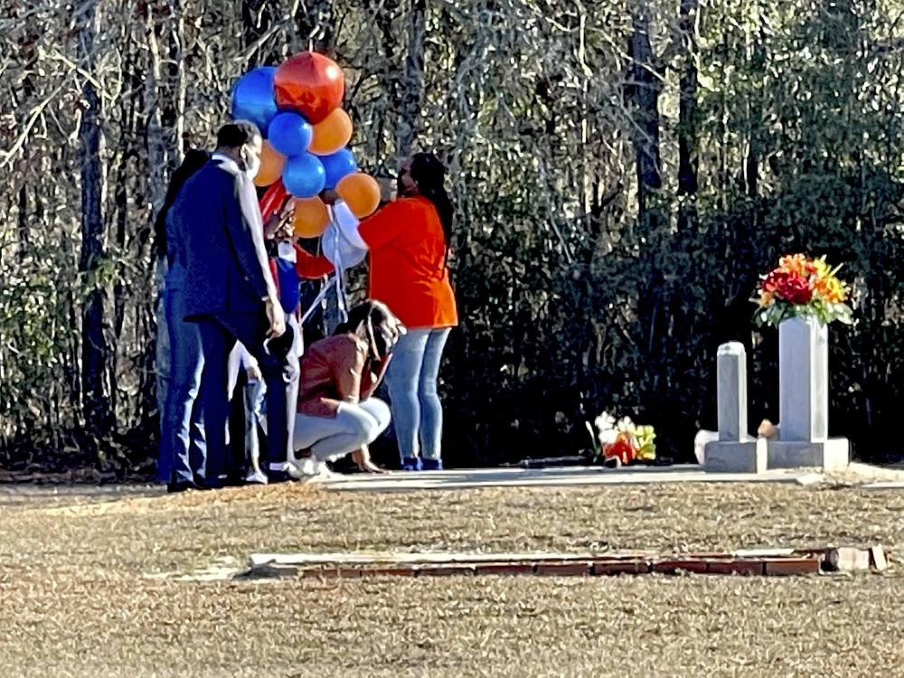 FILE - In this February 23, 2021 file photo, Wanda Cooper-Jones kneels in front of her son Ahmaud Arbery's grave at New Springfield Baptist Church in Waynesboro, Georgia to celebrate the one year anniversary of Ahmaud Arbery's death in Brunswick, Ga. The Justice Department announced on Wednesday April 28, 2021, on charges of hate crimes when Arbery died after being killed during a run.  (AP Photo / Lewis M. Levine, file)