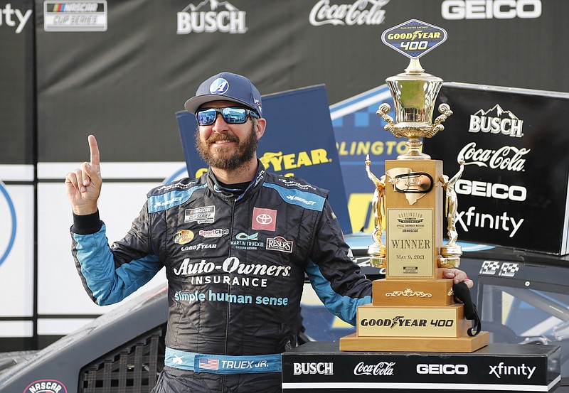 Martin Truex Jr. stands with his trophy in Victory Lane after winning the NASCAR Cup Series auto race at Darlington Raceway, Sunday, May 9, 2021, in Darlington, S.C. (AP Photo/Terry Renna)