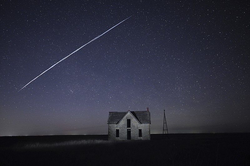 File-In this photo taken May 6, 2021, with a long exposure, a string of SpaceX StarLink satellites passes over an old stone house near Florence, Kan. The train of lights was actually a series of relatively low-flying satellites launched by Elon Musk's SpaceX as part of its Starlink internet service earlier this week.  (AP Photo/Reed Hoffmann, File)