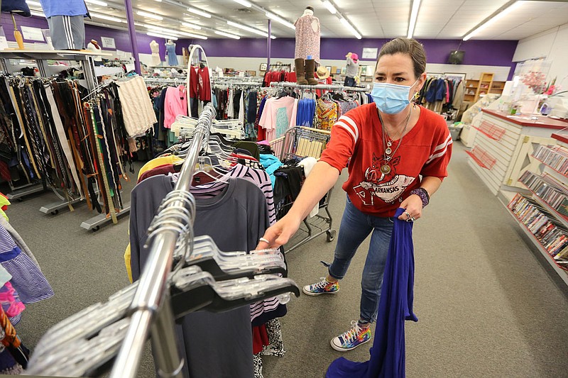 Melissa Eubanks, cashier, hangs clothing items Friday, May 7, 2021, inside the Peace at Home Family Shelter Thrift Store located at 1200 Garland Avenue in Fayetteville. The nonprofit, Peace at Home Family Shelter, has plans to double the size of its emergency shelter, have more outdoor greenspace and build a pet sanctuary in memory of Candy Clark. Check out nwaonline.com/210509Daily/ and nwadg.com/photos for a photo gallery.
(NWA Democrat-Gazette/David Gottschalk)