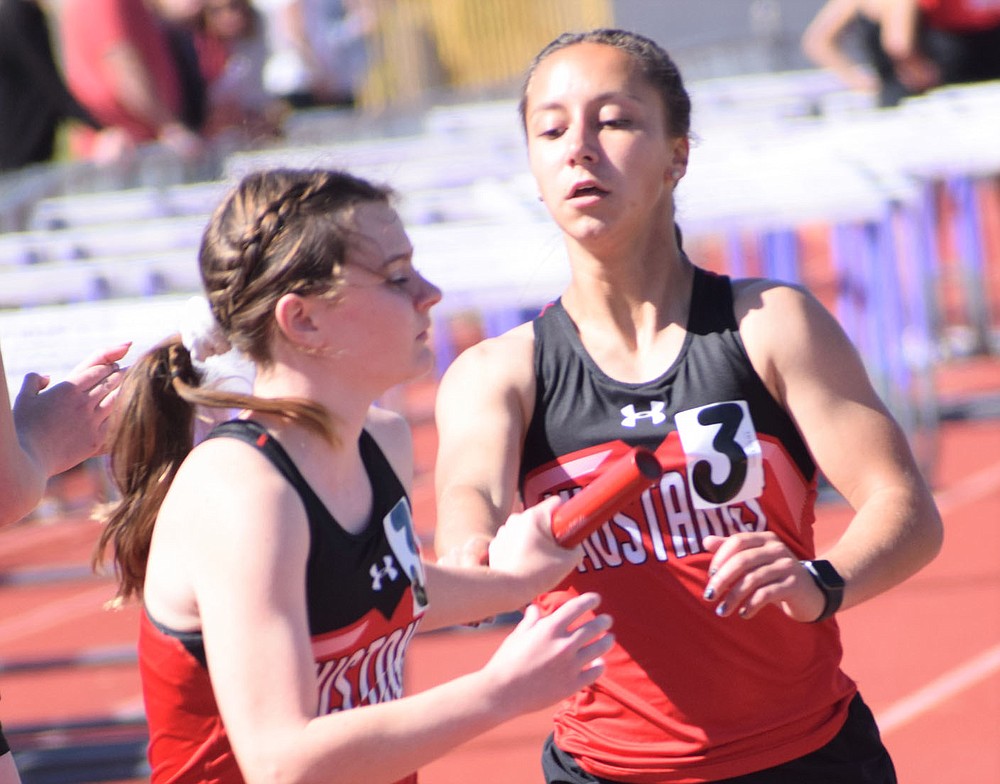 McDonald County's Kaycee Factor makes a hand off to teammate Anna Belle Price during the 4x800 relay at the Big 8 Conference Track and Field Championships held on May 5 at Monett High School. The Lady Mustangs went on to take second in the event.