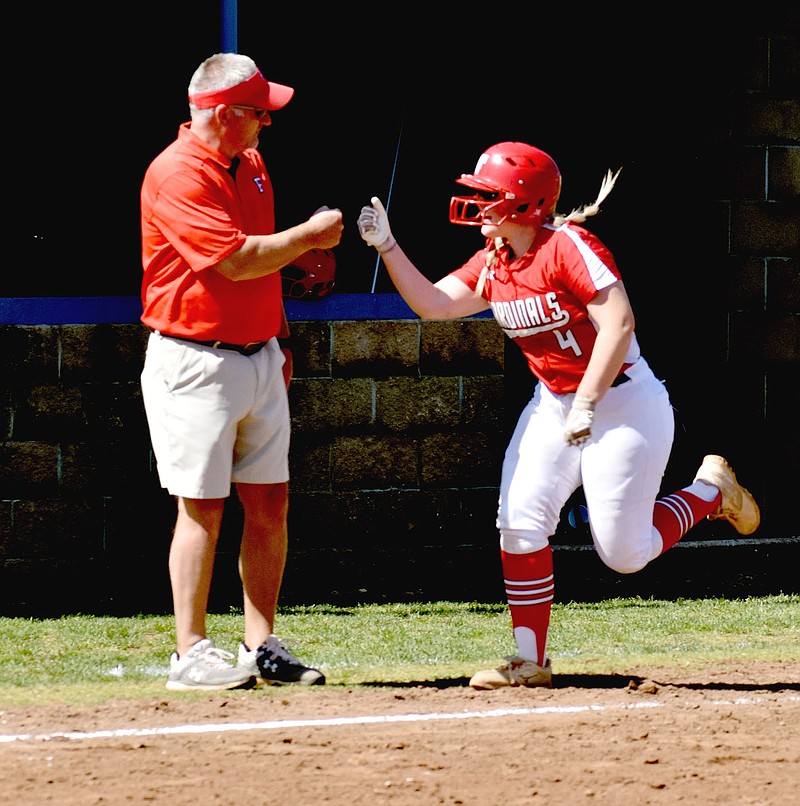 MARK HUMPHREY  ENTERPRISE-LEADER/Farmington senior Grace Boatright (right) receives congratulations from coach Randy Osnes after belting a home run that helped the Lady Cardinals beat Clarksville, 10-2, on Thursday, May 6 during the 4A North Regional softball tournament held at Harrison. The win put the Lady Cardinals into last week’s state tournament at Morrilton. They concluded state play on Saturday with a 5-4 loss to Pea Ridge in the semifinals.