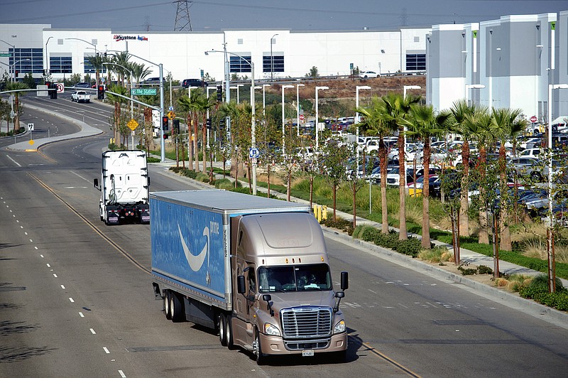 A semi-truck turns into an Amazon Fulfillment center in Eastvale, Calif. on Thursday, Nov. 12, 2020. Southern California air quality regulators are considering a rule that would curb emissions from trucks that ferry goods from the growing number of massive warehouses run by Amazon and other companies. Areas around the facilities have weathered increased pollution affecting largely minority communities. The "warehouse rule" will be voted on, by the South Coast Air Quality Management District. (Watchara Phomicinda/The Orange County Register via AP)