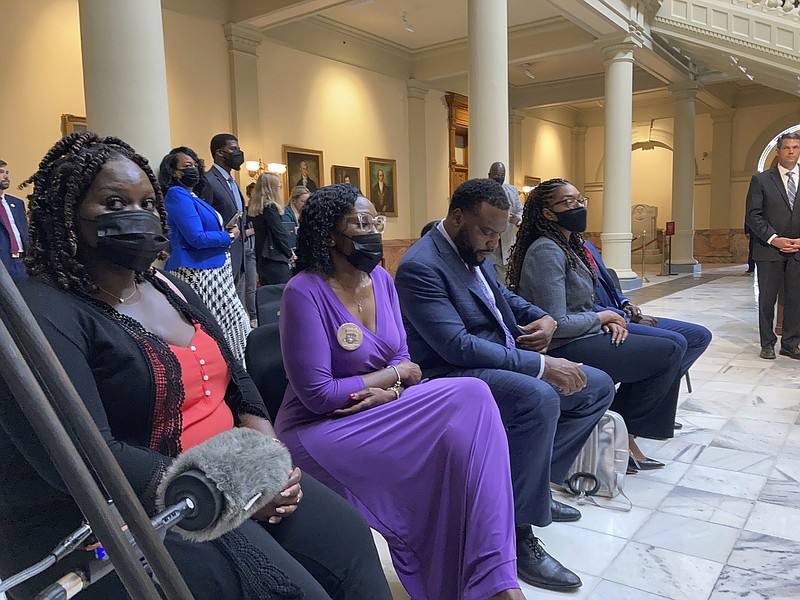 Relatives of Ahmaud Arbery including sister Jasmine Arbery (left) and mother Wanda Cooper Jones (second from left) sit at the Georgia state capitol in Atlanta on Monday, May 10, 2021. They witnessed Georgia Gov. Brian Kemp sign a law repealing citizen's arrest in Georgia, partly blamed for Ahmaud Arbery's fatal shooting death near Brunswick in 2020. (AP Photo/Jeff Amy)