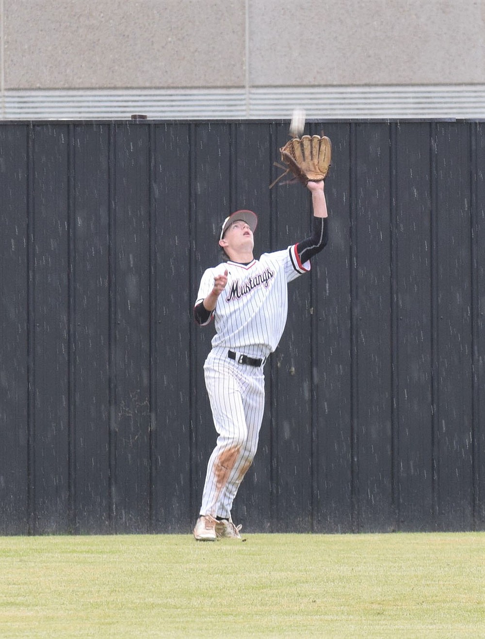 RICK PECK/SPECIAL TO MCDONALD COUNTY PRESS McDonald County center fielder Jack Parnell fights off the raindrops to make a catch in deep center during the Mustangs' 5-5 tie with Republic on May 7 at MCHS.