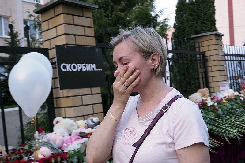 A woman cries near a school after a shooting in Kazan, Russia, Tuesday, May 11, 2021. Writing on the wall reads "We grieve". Russian officials say a gunman attacked a school in the city of Kazan and Russian officials say several people have been killed. Officials said the dead in Tuesday's shooting include students, a teacher and a school worker. Authorities also say over 20 others have been hospitalized with wounds. (AP Photo/Dmitri Lovetsky)
