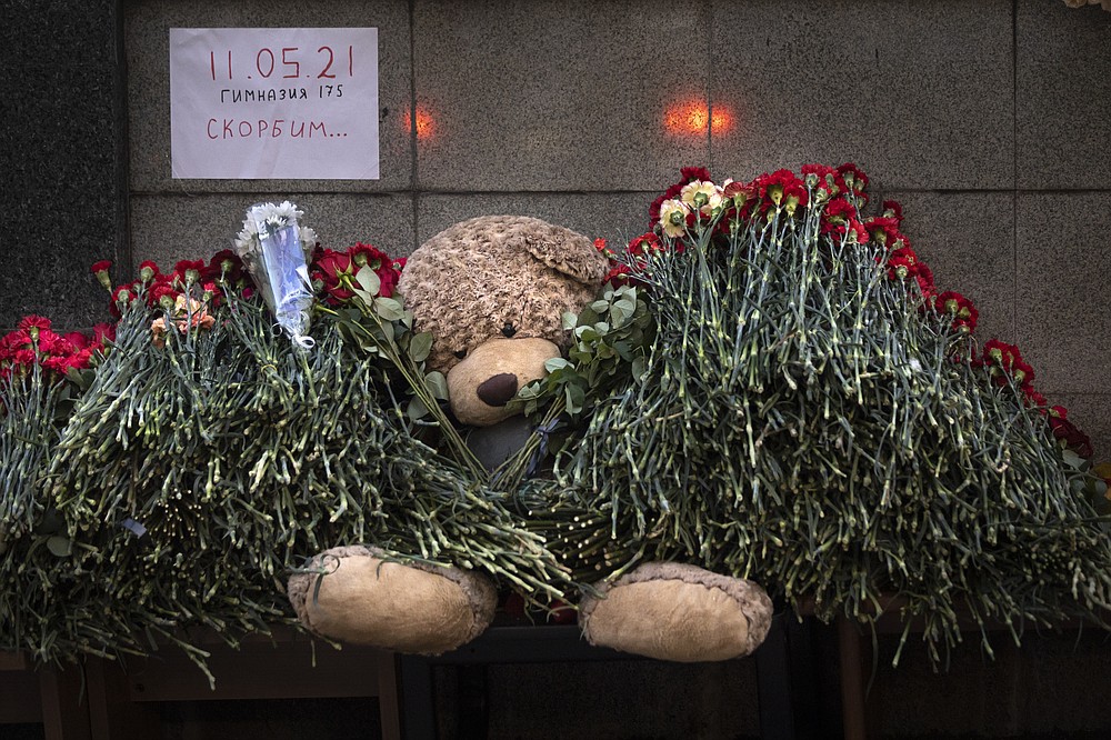 A teddy bear and flowers with the poster reading "11.05.21 School # 175 Mourn" in memory of killed school students in Kazan at the Representation of the Republic of Tatarstan in Moscow, Russia, Tuesday, May 11, 2021. Russian officials say a gunman attacked a school in the city of Kazan and Russian officials say several people have been killed. Officials said the dead in Tuesday's shooting include students, a teacher and a school worker. Authorities also say over 20 others have been hospitalized with wounds. (AP Photo/Alexander Zemlianichenko)