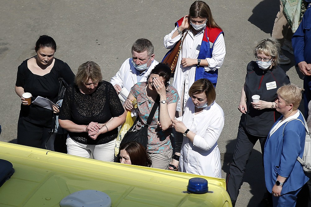 Medics and friends help a woman board an ambulance at a school after a shooting in Kazan, Russia, Tuesday, May 11, 2021. Russian media report that several people have been killed and four wounded in a school shooting in the city of Kazan. Russia's state RIA Novosti news agency reported the shooting took place Tuesday morning, citing emergency services. (AP Photo/Roman Kruchinin)