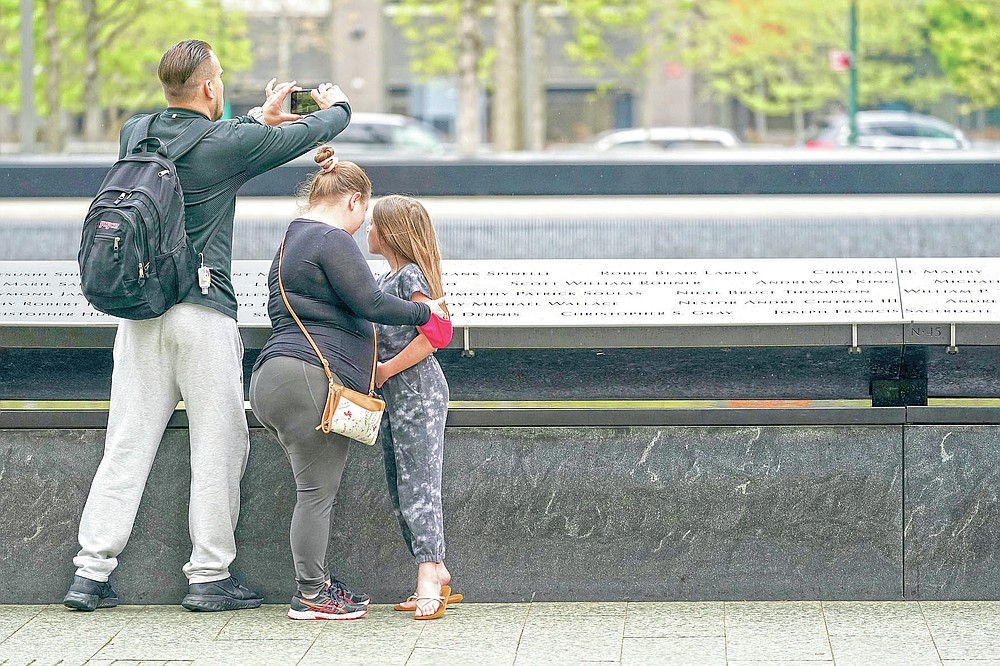 Visitors to the 9/11 Memorial and Museum take in the view of the North Pool, Thursday, April 29, 2021, in New York. In recent weeks, tourism indicators for New York City like hotel occupancy and museum attendance that had fallen off a pandemic cliff have ticked up slightly. It's a welcome sight for a city where the industry has been decimated by the impact of the coronavirus. (AP Photo/Mary Altaffer)