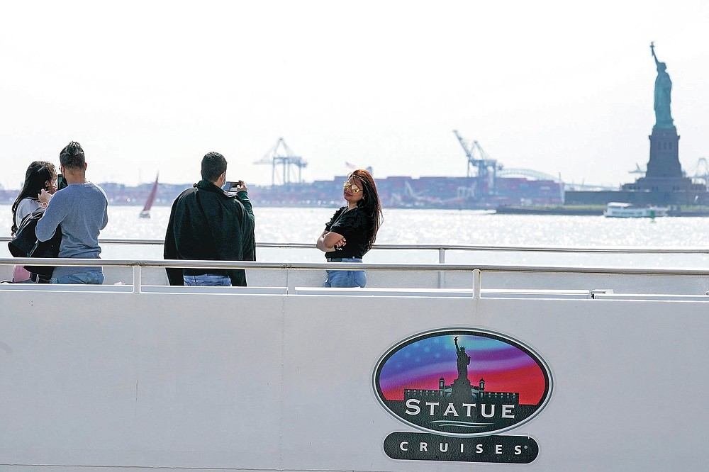 Visitors take photos after boarding the Statue of Liberty ferry, Tuesday, April 27, 2021, in New York. In recent weeks, tourism indicators for New York City like hotel occupancy and museum attendance that had fallen off a pandemic cliff have ticked up slightly. It's a welcome sight for a city where the industry has been decimated by the impact of the coronavirus. (AP Photo/Mary Altaffer)