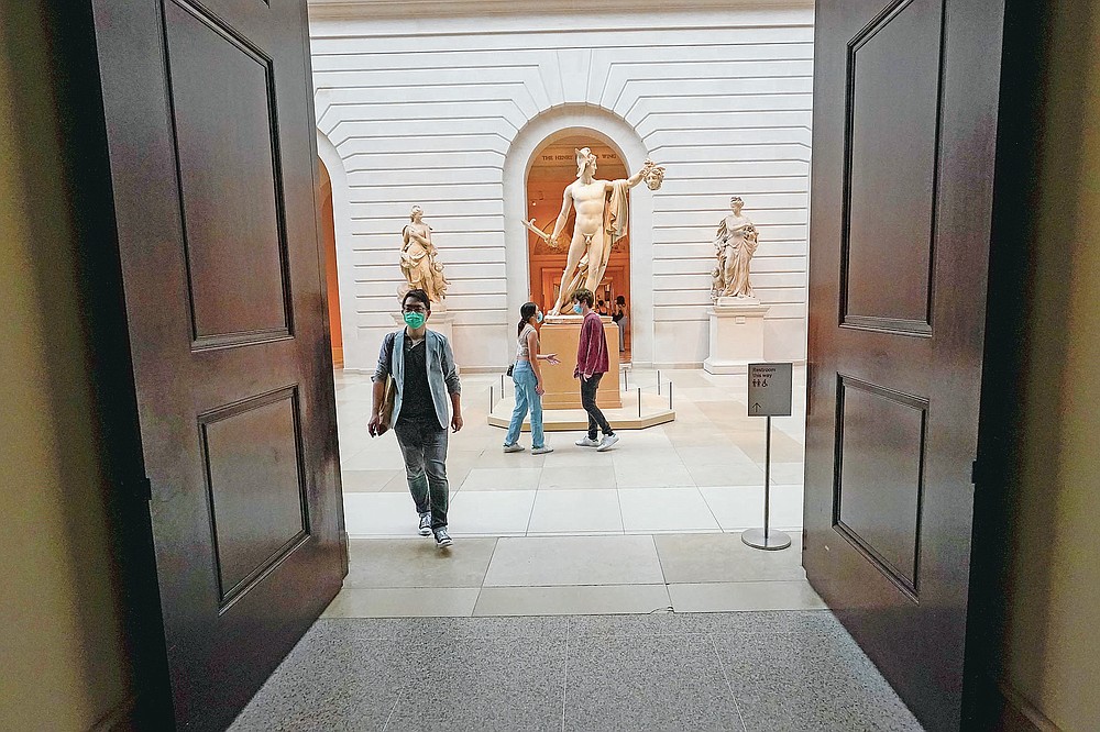 Visitors to the Metropolitan Museum of Art walk past Antonio Canova's "Perseus with the Head of Medusa," Thursday, April 29, 2021, in New York. In recent weeks, tourism indicators for New York City like hotel occupancy and museum attendance that had fallen off a pandemic cliff have ticked up slightly. It's a welcome sight for a city where the industry has been decimated by the impact of the coronavirus. (AP Photo/Mary Altaffer)