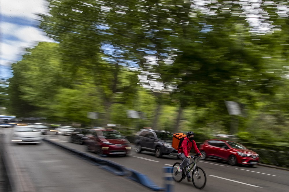 Un trabajador de reparto monta su bicicleta en Madrid, España, el martes 11 de mayo de 2021. España aprobó una ley innovadora que otorga a las plataformas de reparto una fecha límite a mediados de agosto para contratar trabajadores que actualmente son autónomos y requiere transparencia de IA para gestionar la fuerza laboral .  (Foto AP / Manu Fernandez)