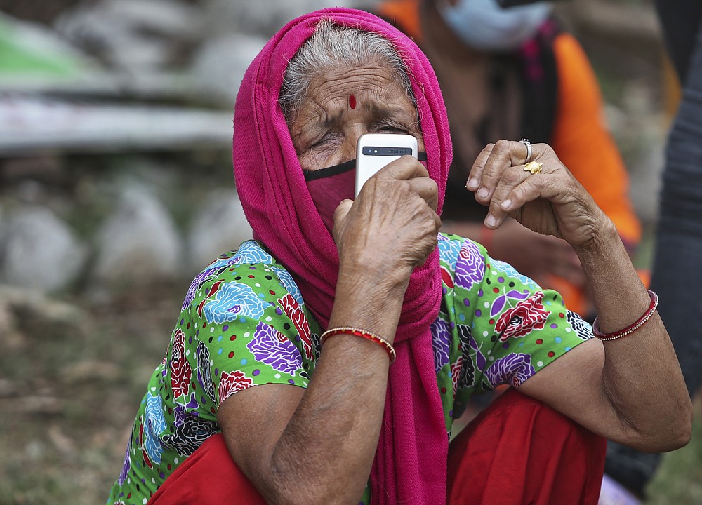 A woman wearing face mask as a precaution against the coronavirus talks on the mobile phone as she waits to get tested for COVID-19 in Jammu, India, Wednesday, May 12, 2021. Misinformation about the coronavirus is surging in India as the death toll from COVID-19 rises. Fueled by anguish, distrust and political polarization, the claims are further compounding India's crisis. (AP Photo/Channi Anand)