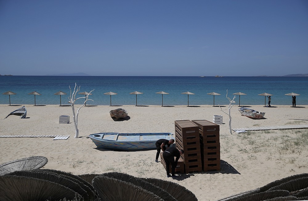 Οι εργαζόμενοι κανονίζουν ξαπλώστρες, ενώ άλλοι εγκαθιστούν ομπρέλες στην παραλία της Πλάκας στη Νάξο στην Ελλάδα, Τετάρτη 12 Μαΐου 2021. Με το χρέος να συσσωρεύεται, οι χώρες της Νότιας Ευρώπης αγωνίζονται να ανοίξουν ξανά τις τουριστικές υπηρεσίες τους παρά τις καθυστερήσεις στην έναρξη του προγραμματισμένου σχεδίου της ΕΕ - δήλωση Wide travel .  Την Παρασκευή, η Ελλάδα έγινε η τελευταία χώρα που άνοιξε την περίοδο των διακοπών της, καθώς άφησε τους περιορισμούς κλειδώματος και εστίασε το πρόγραμμα εμβολιασμού της στα νησιά.  (Φωτογραφία AP / Θανάσης Σταυράκης)