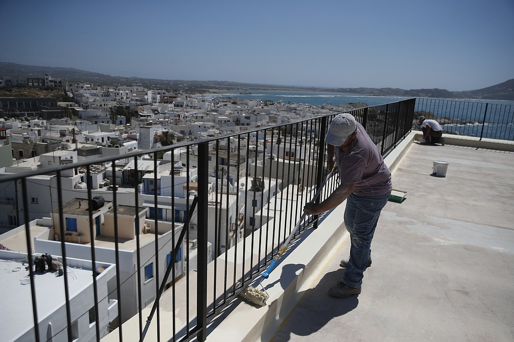 Οι εργαζόμενοι ζωγραφίζουν το μπαλκόνι ενός καφενείου που είναι ανοιχτό όλη μέρα στη Χώρα, στο νησί του Νησιού, στο Αιγαίο, Τρίτη 11 Μαΐου 2021 (AP Photo / Θανάσης Σταυράκης)