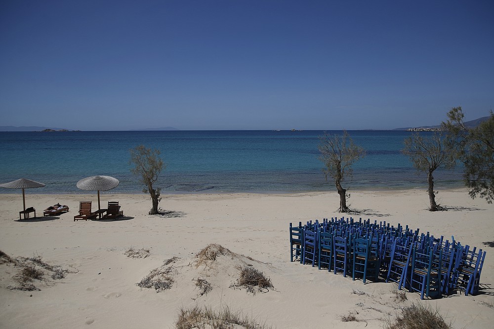 Ένας τουρίστας απολαμβάνει τον ήλιο καθώς οι ξαπλώστρες αποθηκεύονται στην παραλία της Πλάκας της Νάξου στην Ελλάδα, Τετάρτη 12 Μαΐου 2021. Με το χρέος να συσσωρεύεται, οι χώρες της νότιας Ευρώπης αγωνίζονται να ανοίξουν ξανά τις τουριστικές τους υπηρεσίες παρά τις καθυστερήσεις στην έκδοση μιας προγραμματισμένης άδειας ταξιδιού σε επίπεδο Ευρωπαϊκής Ένωσης.  Την Παρασκευή, η Ελλάδα έγινε η τελευταία χώρα που άνοιξε την περίοδο των διακοπών της, καθώς άφησε τους περιορισμούς κλειδώματος και εστίασε το πρόγραμμα εμβολιασμού της στα νησιά.  (Φωτογραφία AP / Θανάσης Σταυράκης)