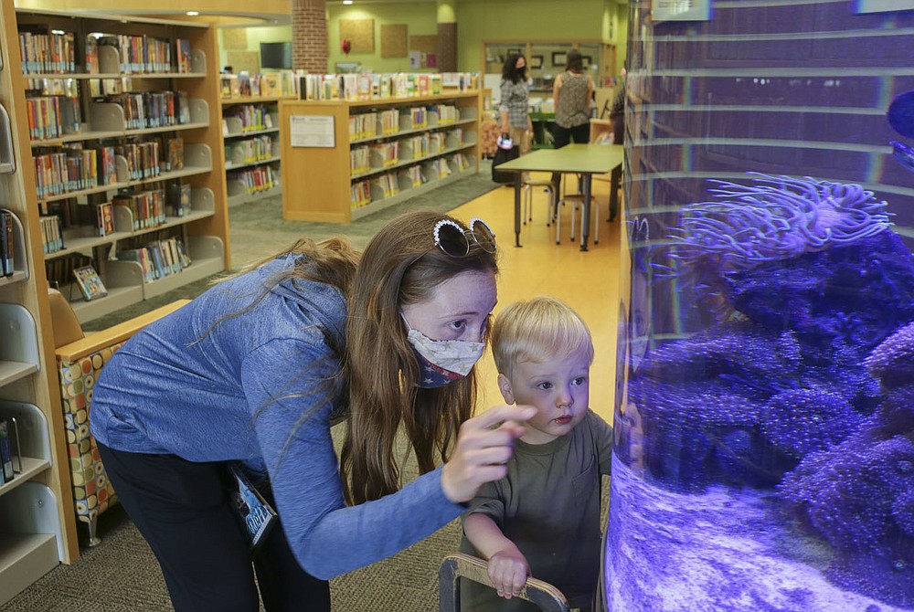 Rachel Burge of Bentonville (from left) and Cody Burge, 2, look into an aquarium, Thursday, May 13, 2021 at the Bentonville Library in Bentonville. The Bentonville Library Foundation plans to raise 10.5 million to the full needs assessment plan.
(NWA Democrat-Gazette/Charlie Kaijo)