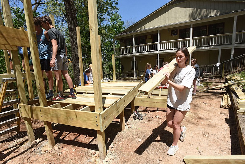 Kathryn Brown (right) shoulders a load of lumber on Saturday May 8 2021 during the playground build in Little Flock by Shiloh Christian School students.
(NWA Democrat-Gazette/Flip Putthoff)