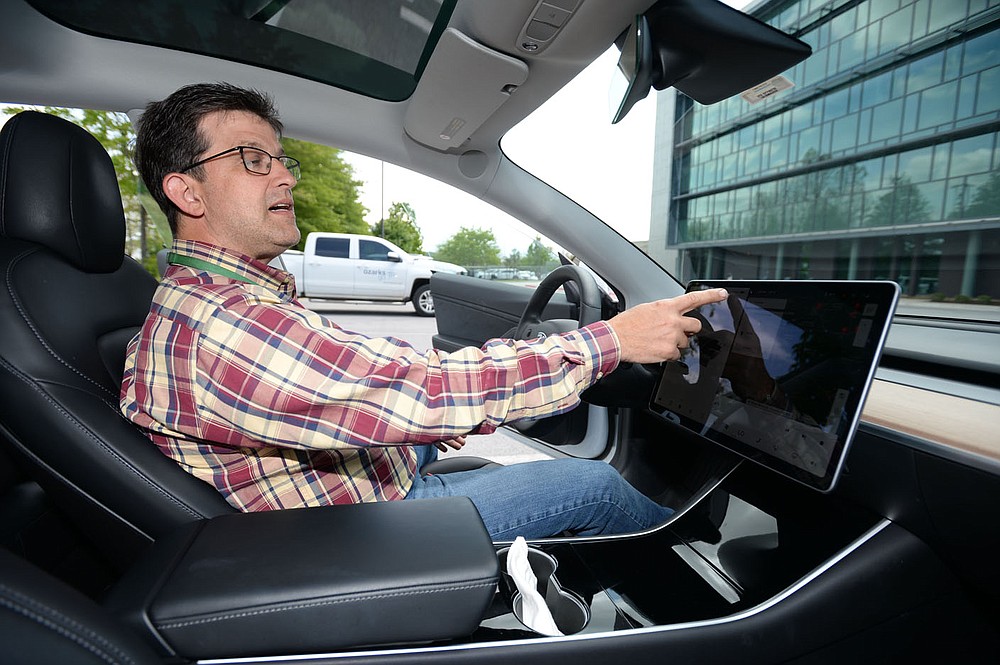 Kris Williams, director of energy services for Ozarks Electric Cooperative Corp. demonstrates the navigation system of the cooperative√çs Tesla Model 3 electric vehicles assists in planning a route to a destination with consideration of where charging stations are located Wednesday, May 12, 2021, at the cooperative√çs offices in Fayetteville. It can be challenging to find charging stations for electric vehicles in rural areas of Arkansas, but both the state and private companies are working to change that. Visit nwaonline.com/210518Daily/ for today's photo gallery. (NWA Democrat-Gazette/Andy Shupe)