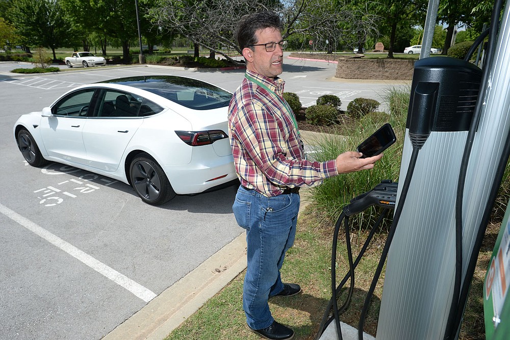 Kris Williams, director of energy services for Ozarks Electric Cooperative Corp. demonstrates how one of the cooperative‚Ä∞√õ¬™s Tesla Model 3 electric vehicles is charged Wednesday, May 12, 2021, at the cooperative‚Ä∞√õ¬™s offices in Fayetteville. It can be challenging to find charging stations for electric vehicles in rural areas of Arkansas, but both the state and private companies are working to change that. Visit nwaonline.com/210518Daily/ for today's photo gallery. (NWA Democrat-Gazette/Andy Shupe)