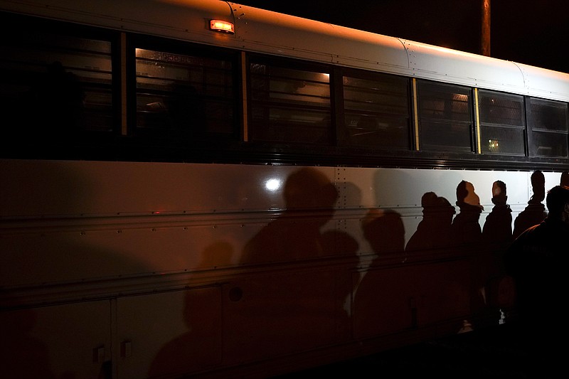FILE - In this May 11, 2021, file photo shadows of migrants lined up at an intake area are cast along the side of a bus after turning themselves in upon crossing the U.S.-Mexico border in Roma, Texas. President Joe Biden, under political pressure, agreed to admit four times as many refugees this budget year as his predecessor did, but resettlement agencies concede the number actually allowed into the U.S. will be closer to the record-low cap of 15,000 set by former President Donald Trump. (AP Photo/Gregory Bull, File)