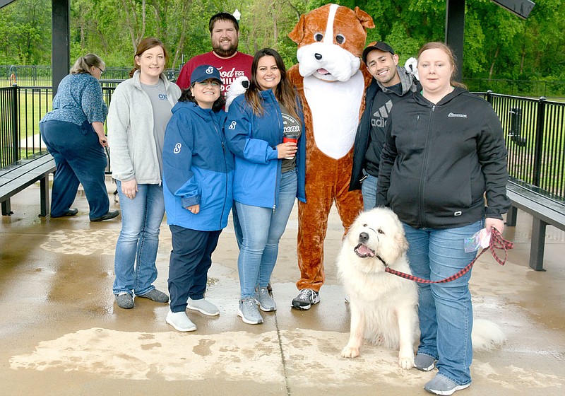 Marc Hayot/Herald-Leader Robert Prelle (third from right), the unofficial mascot for Simmons Food's pet food division poses with (l-r) Katrina Newman, Karina Tun, Jack Outlaw, Bernice Spence, Alex Castaneda, Cotton, and Candace Campbell at Bark in the Park on Saturday. Simmons was one of the vendors at Bark in the Park.